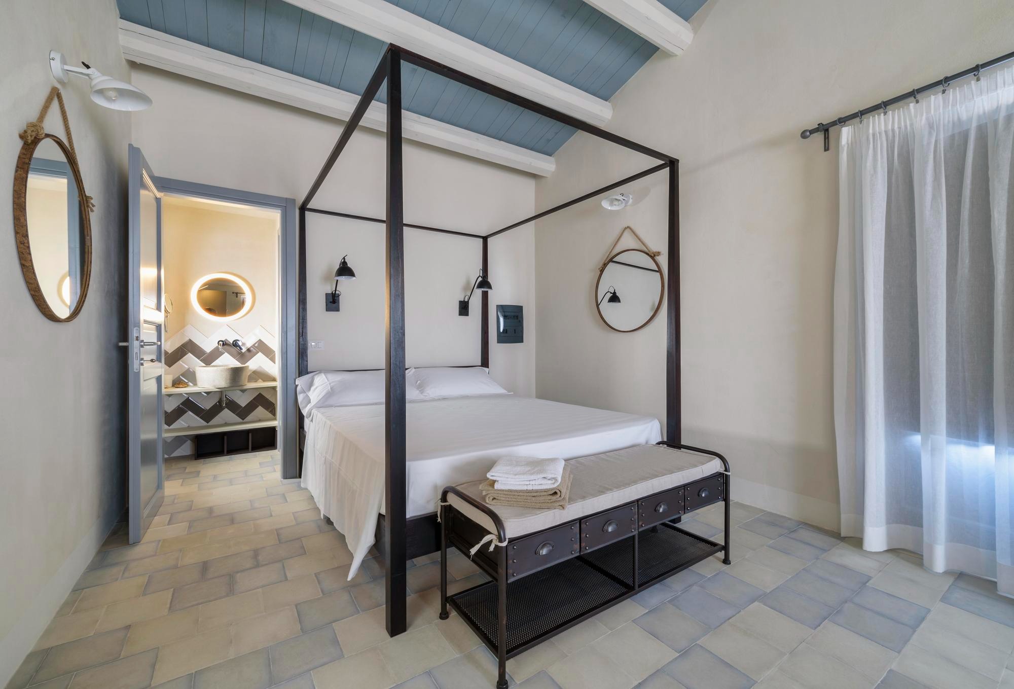 Dormitorio mediterráneo con cama de dosel y techo de vigas blancas y azul pastel