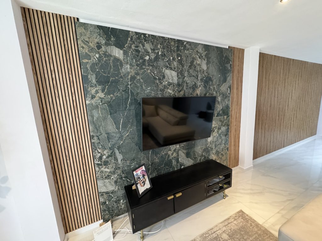 Decoración de pared con mármol y madera en salón contemporáneo con televisión
