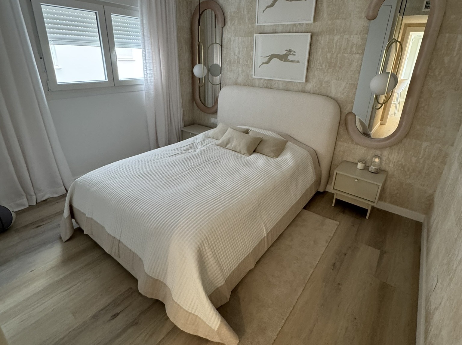 IMG_6953 Dormitorio moderno con cama tapizada beige, espejos de diseño y lámparas colgantes". "Habitación acogedora con decoración simétrica, cuadros y detalles en tonos neutros