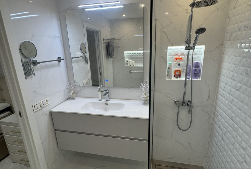 Baño moderno con lavabo flotante, espejo LED y ducha con mampara de cristal