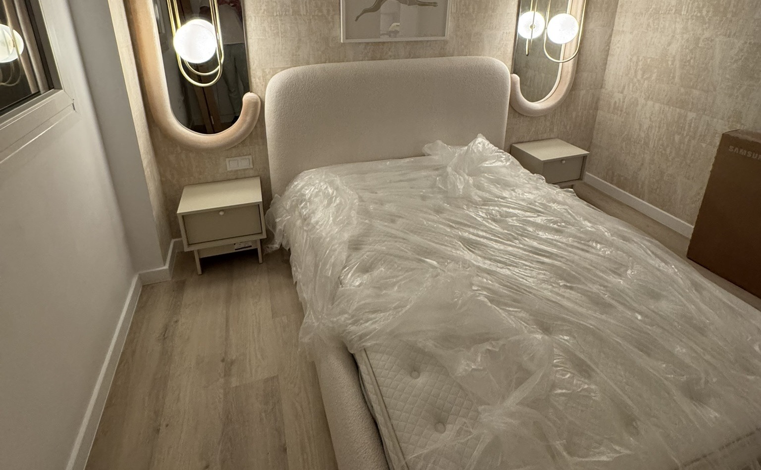 Dormitorio moderno con cama tapizada y lámparas integradas en espejos decorativos
