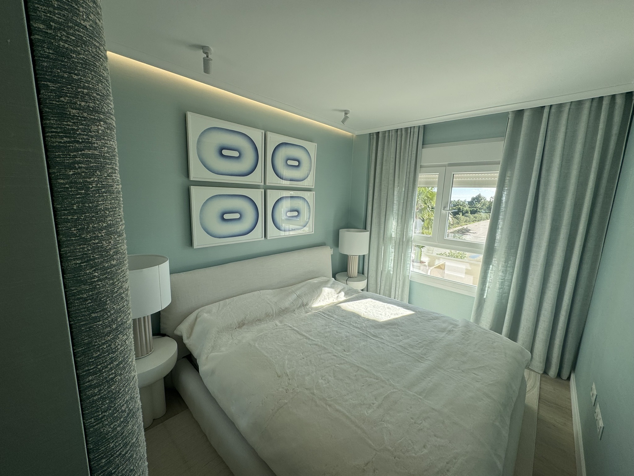 Dormitorio moderno con decoración en tonos azules, cama doble y cuadros abstractos