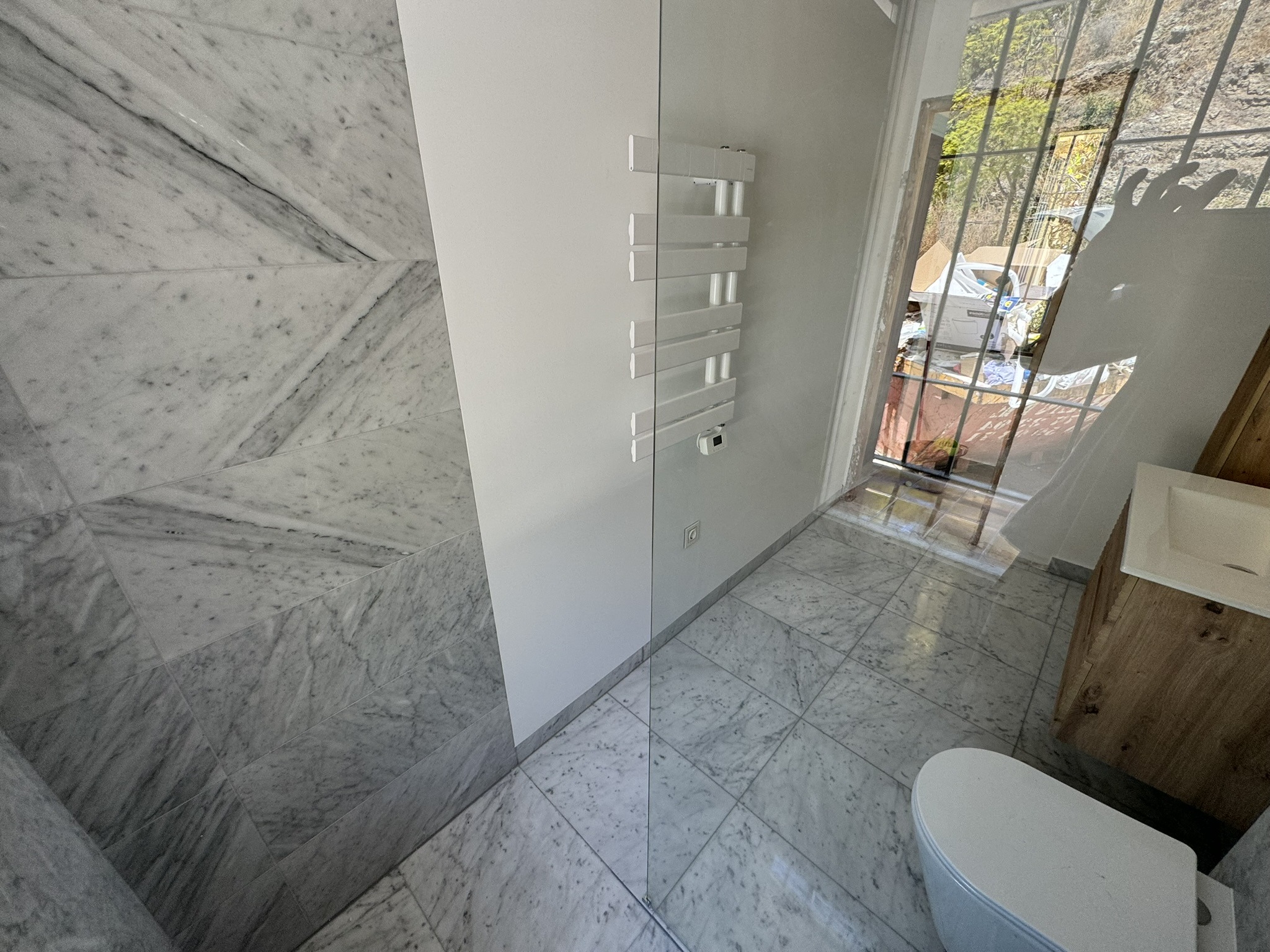 Baño moderno con revestimiento de mármol gris y toallero calefactable