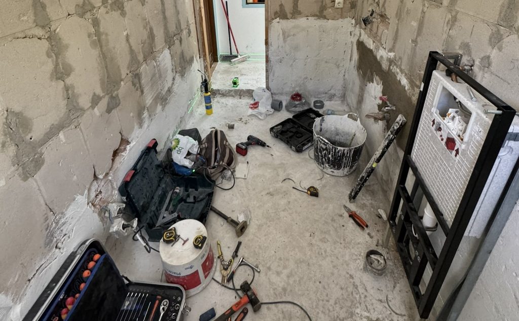 Baño en reforma con cisterna empotrada y herramientas de obra
