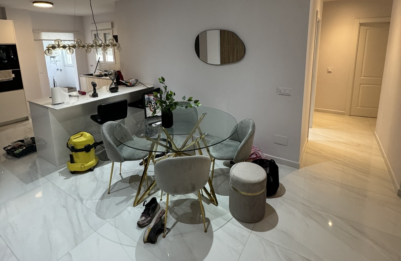 Comedor moderno con mesa de cristal y cocina integrada en proceso de obra