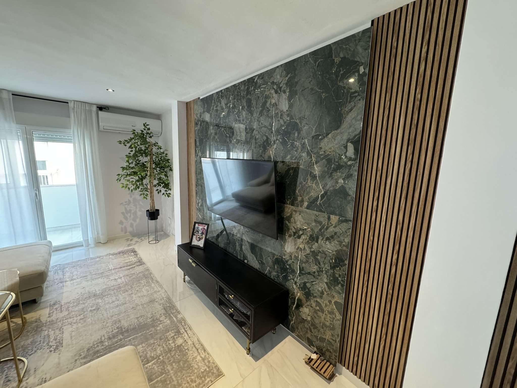 Salón moderno con pared de mármol oscuro y paneles de madera decorativos