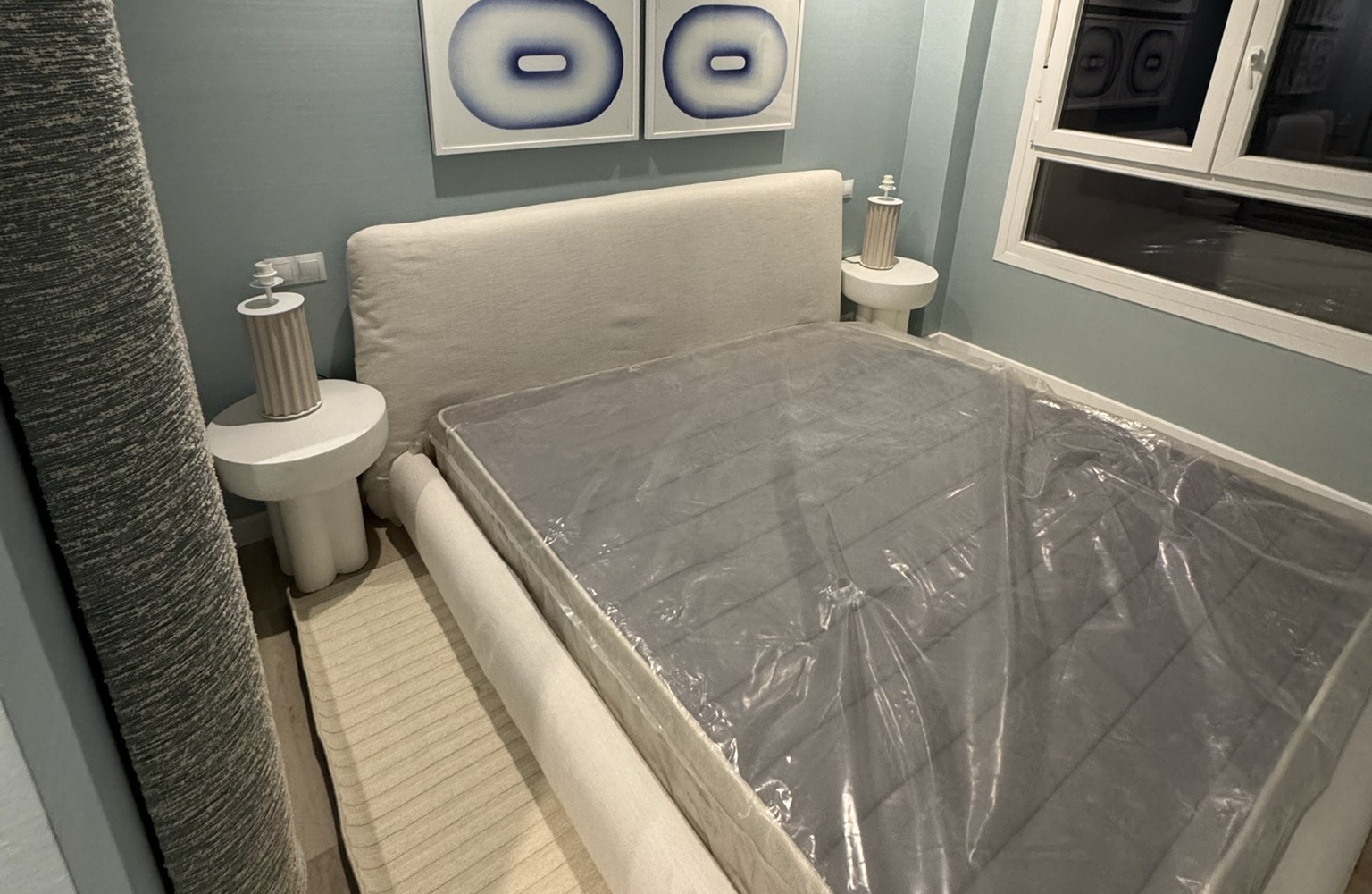 Dormitorio moderno en proceso de montaje con cama tapizada y decoración en tonos azules